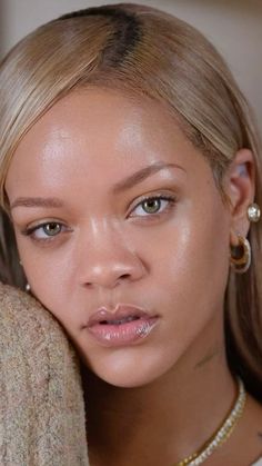 a close up of a woman with blonde hair and piercings on her ear wearing gold jewelry