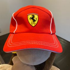 a stuffed animal wearing a red hat with a ferrari emblem on it's side