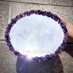 a hand holding a glass plate with purple flowers on it and the sky in the background