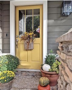 a yellow front door with pumpkins and gourds