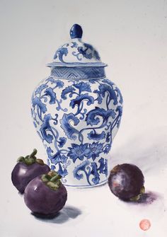 a blue and white vase sitting next to two plums