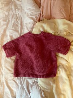 a baby sweater laying on top of a bed