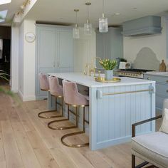 a kitchen with blue cabinets and white counter tops next to a dining room table filled with chairs