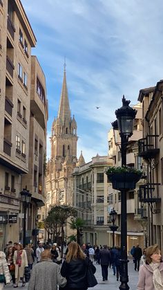 people are walking down the street in an old european city with tall buildings on either side