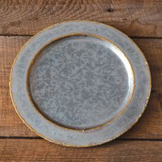 a gray and gold plate sitting on top of a wooden table