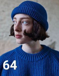 a woman with a moustache wearing a blue sweater and a knitted hat