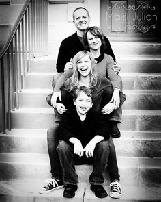 a black and white photo of a family sitting on the stairs