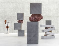 an abstract sculpture made out of concrete blocks and rocks with one rock sticking out of it