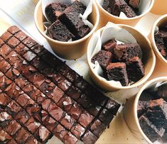 several bowls filled with brownies on top of a table next to a tray of chocolate squares