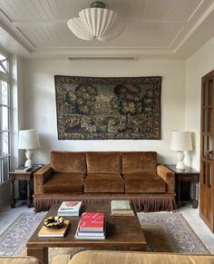 a living room filled with furniture and a large tapestry hanging on the wall above it