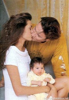 a man and woman kissing a baby on the cheek while sitting next to each other