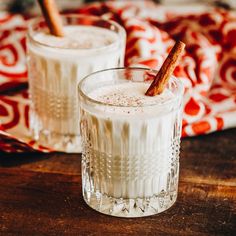 two glasses filled with drink sitting on top of a wooden table