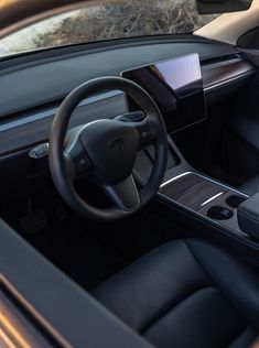 the interior of a modern car with black leather seats and steering wheel, including an electronic display screen