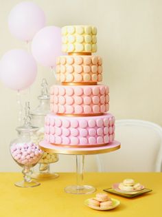 a three tiered cake sitting on top of a table next to pink and white balloons