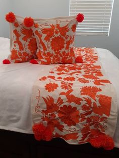 an orange and white comforter with pom poms on the pillowcases