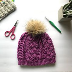 a knitted hat with a pom - pom sitting on top of it