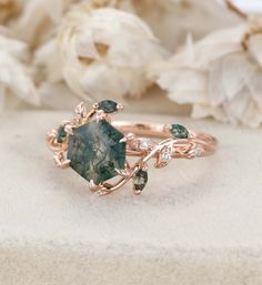 a close up of a ring on a table with flowers in the background and a white flower