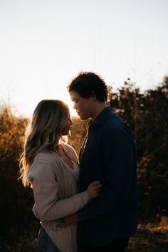 a man and woman standing next to each other with the sun shining through their eyes