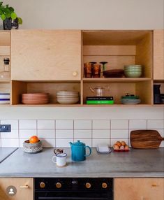 a kitchen counter with bowls and plates on it, next to a wooden shelf filled with dishes