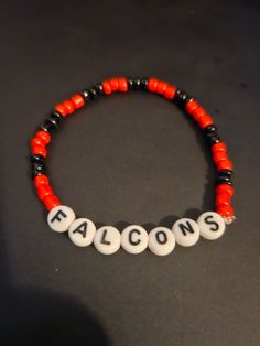 an orange and black beaded bracelet with the word falcons written on it