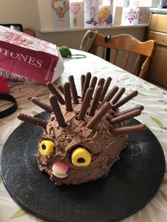 a cake shaped like a hedgehog sitting on top of a black plate with chocolate frosting