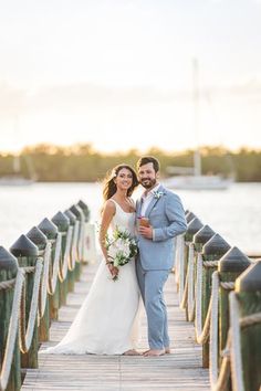 a bride and groom standing on a pier