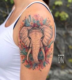 an elephant tattoo on the left arm and shoulder, with flowers all over its body