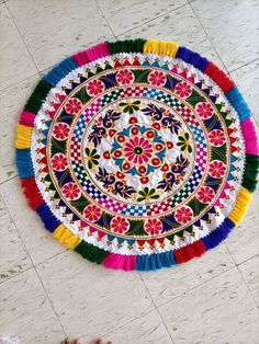 a colorful round rug with tassels on the floor next to a pair of sandals