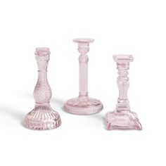 three pink glass candlesticks sitting next to each other