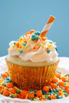 a cupcake with white frosting and sprinkles is on a plate