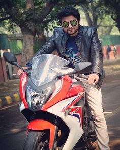 a man in sunglasses is sitting on a red and white motorcycle with trees in the background