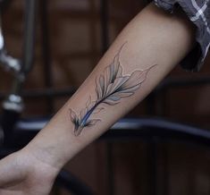 a woman's arm with a tattoo on it and a blue feather in the middle