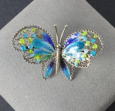 Very sweet spun silver butterfly brooch marked 800 on the reverse, He is made of spun silver and displays gorgeous enamel in bright shades of blue and green. Height:   1 inch Width:     1  5/8 inches In very good vintage condition! Collectible Hallmarked Blue Brooches, Multicolor Butterfly Brooch Jewelry, Blue Enamel Brooch Gift, Blue Enamel Brooch For Gift, Blue Enamel Brooches For Gift, Green Sterling Silver Brooch For Gift, Green Sterling Silver Brooches For Gifts, Green Sterling Silver Brooches As Gifts, Elegant Blue Butterfly Brooches