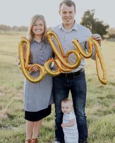 a man and woman holding up an air filled balloon that says golly in front of them