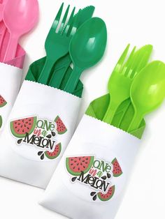 three plastic utensils with one green and one pink on them, sitting next to each other