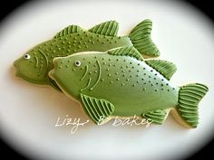 two green fish cookies sitting on top of a white plate with the words happy birthday written below them