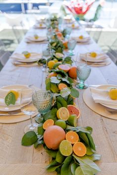 a long table is set with fruit and greenery for a festive dinner party