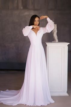 a woman in a white dress standing next to a statue