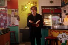 a man standing in front of a counter holding a book