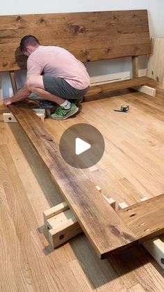 a man laying on top of a wooden bed frame in the middle of a room