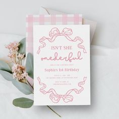 a pink and white checkered birthday card with flowers next to it on top of a table