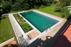 an aerial view of a swimming pool in the middle of a yard with grass and trees