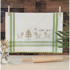 a kitchen towel hanging on a clothes line next to a small christmas tree in a vase