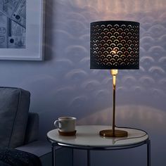 a table with a lamp on it and a coffee cup next to it in front of a blue wall