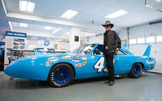 a man standing next to a blue race car