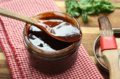 a wooden spoon sitting on top of a jar filled with liquid next to a cutting board