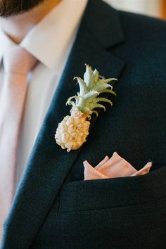 a man in a suit with a pineapple boutonniere on his lapel