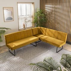 a yellow couch sitting on top of a rug in a living room next to a plant