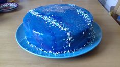 a blue cake with white sprinkles on a blue plate sitting on a wooden table