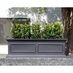 two planters are sitting on the side of a building with trees in the background